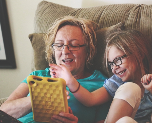 Parent and child using a tablet on the couch together