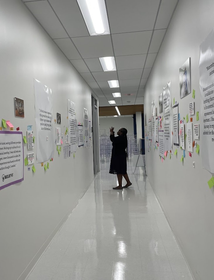 Picture of a long hallway, with posters and quotes stuck to the walls. A student can be seen taking photos at the end of the hallway.